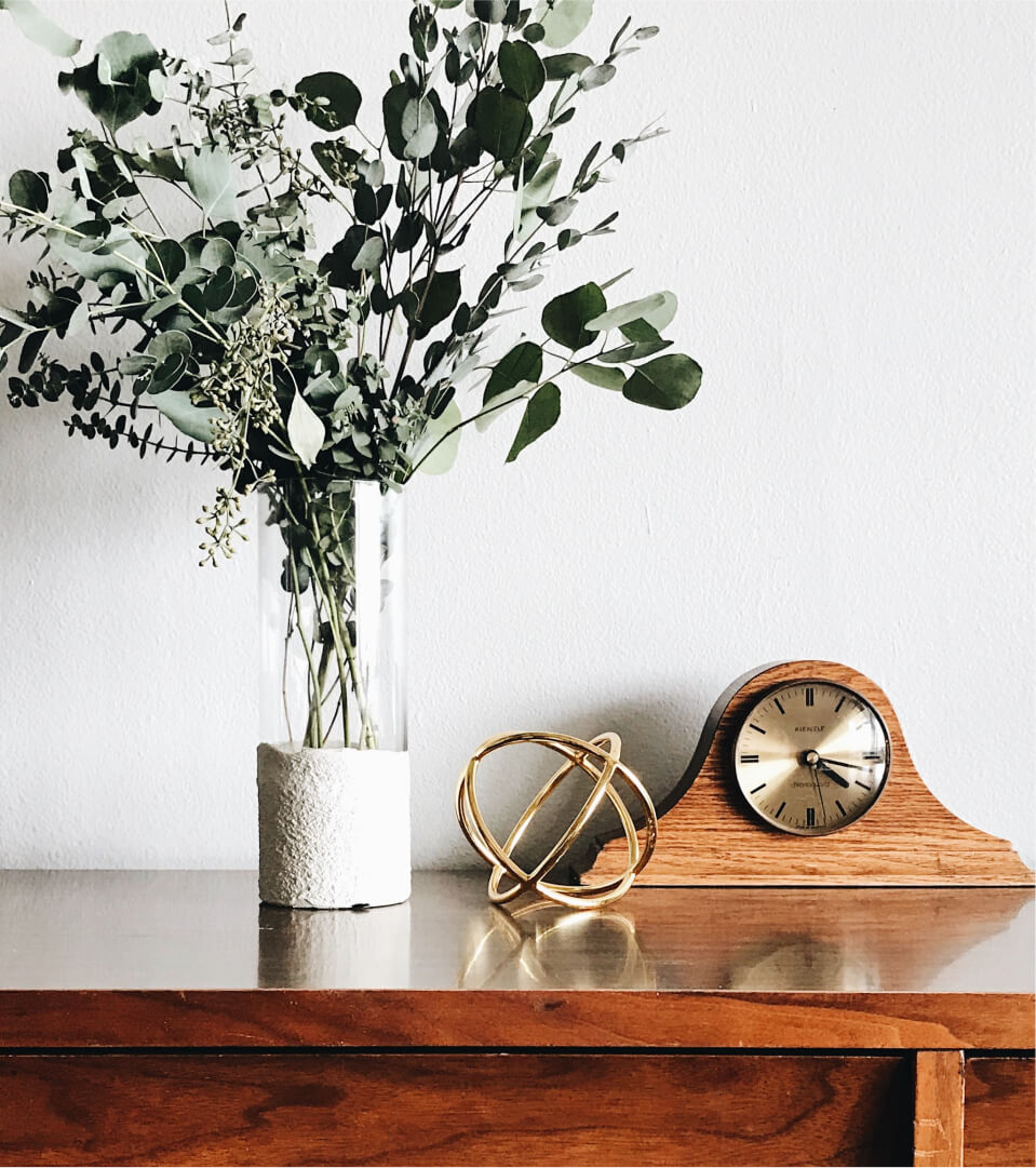 vintage clock next to vase of eucalyptus branches